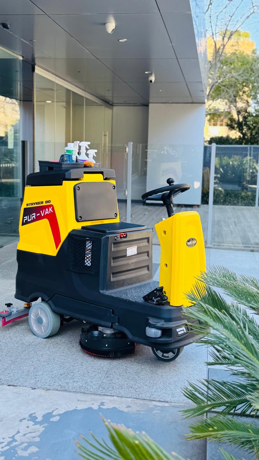 Yellow Purvak Stryker 80 ride-on floor scrubber outside a commercial building